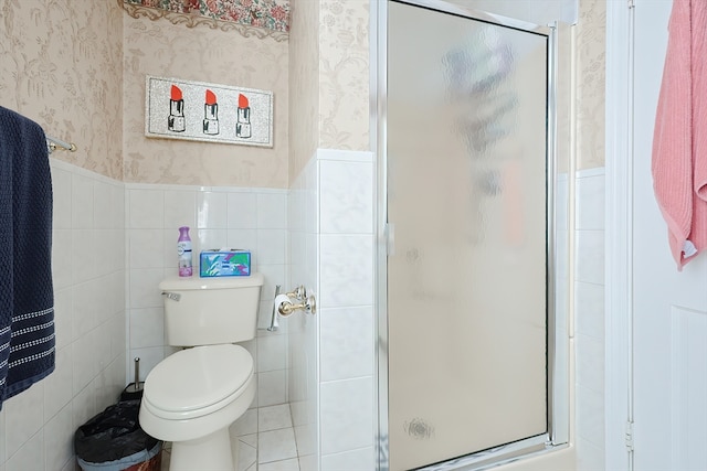 bathroom featuring a shower with door, tile walls, and toilet