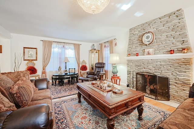 living room with a stone fireplace, a notable chandelier, and light wood-type flooring