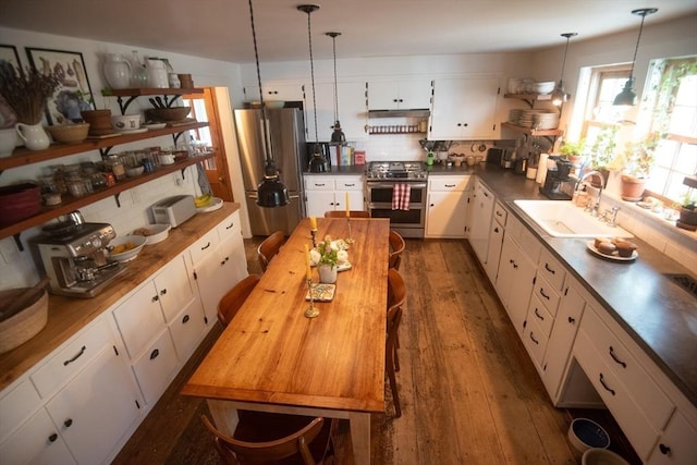 kitchen featuring stainless steel appliances, a sink, backsplash, and pendant lighting