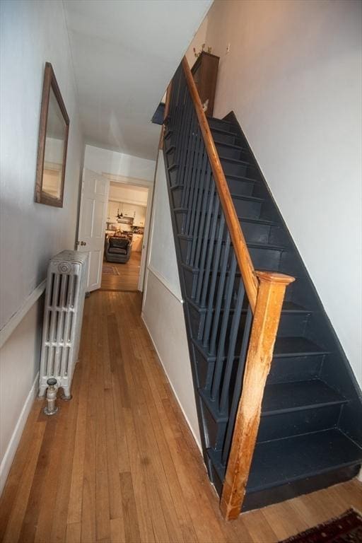 stairs with radiator, hardwood / wood-style flooring, and baseboards