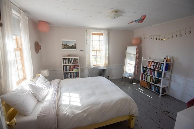 bedroom with radiator, ornamental molding, and a wainscoted wall
