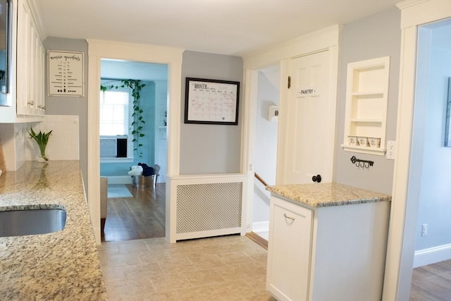 24 Garey St, Weymouth, MA 02189 - kitchen with radiator, white cabinetry, light stone counters, decorative backsplash, and built in shelves