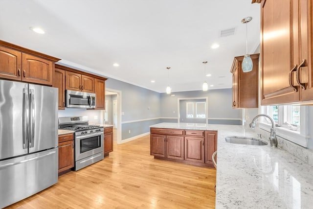 kitchen with a sink, brown cabinetry, stainless steel appliances, and a peninsula