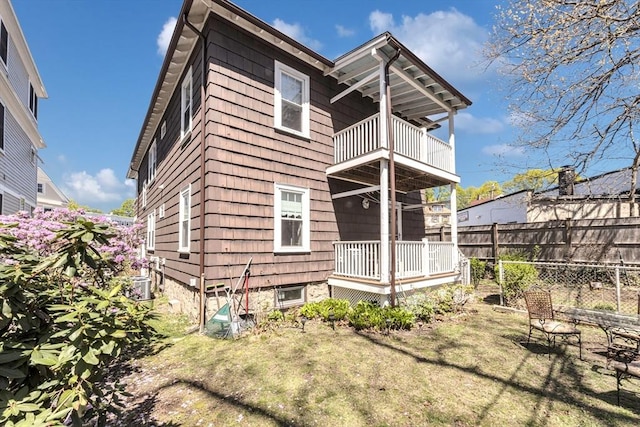 back of house featuring a yard, fence, a balcony, and central air condition unit