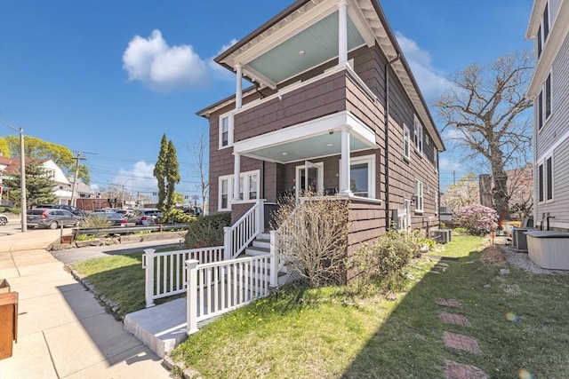 view of front of property with a porch, a front lawn, central air condition unit, and a balcony