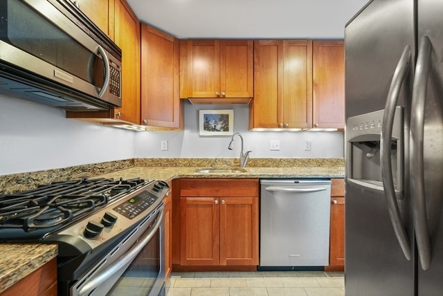 kitchen featuring light tile patterned flooring, light stone counters, stainless steel appliances, and sink