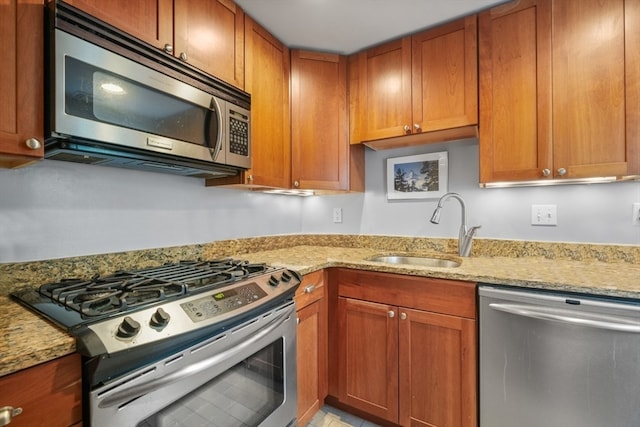 kitchen featuring sink, light stone countertops, and appliances with stainless steel finishes