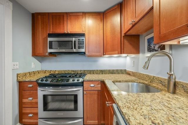 kitchen with sink, light stone countertops, and appliances with stainless steel finishes