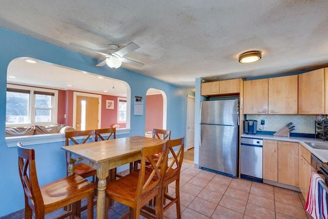 kitchen featuring light tile patterned floors, ceiling fan, appliances with stainless steel finishes, tasteful backsplash, and light brown cabinets