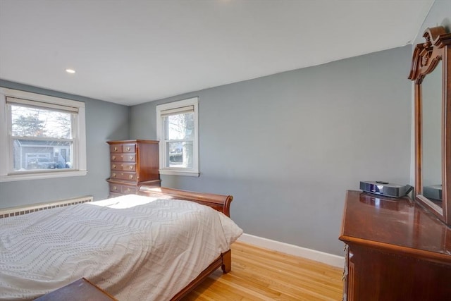 bedroom with a baseboard radiator and light hardwood / wood-style flooring