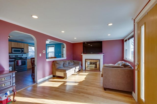 living room featuring ornamental molding, a brick fireplace, and light hardwood / wood-style flooring