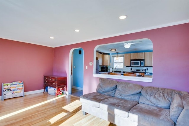 living room featuring ornamental molding, sink, and light hardwood / wood-style floors