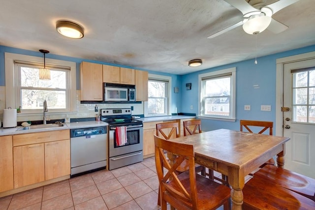 kitchen with pendant lighting, sink, stainless steel appliances, and light brown cabinets