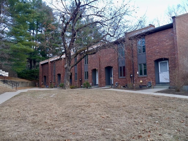 view of front facade with entry steps, a front lawn, and brick siding