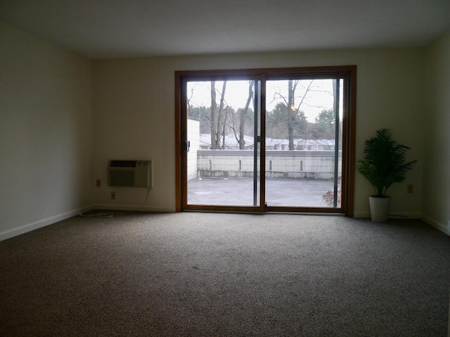 carpeted empty room featuring a wall unit AC and baseboards