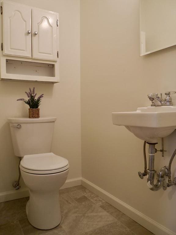 half bathroom with toilet, tile patterned flooring, and baseboards