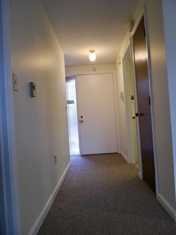 hallway with carpet flooring and baseboards