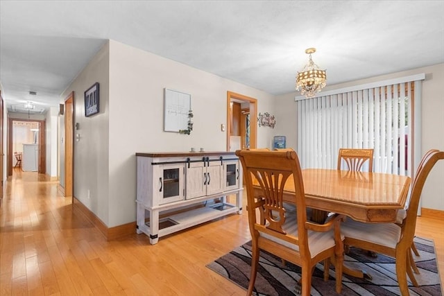 dining space featuring light wood-style floors, baseboards, and an inviting chandelier