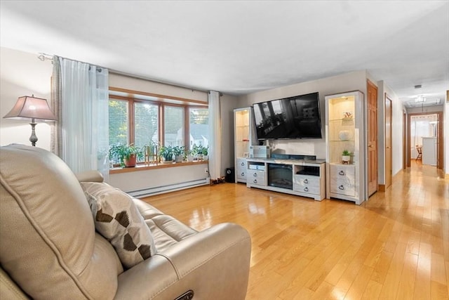 living room featuring light wood-style floors, a baseboard radiator, and baseboards