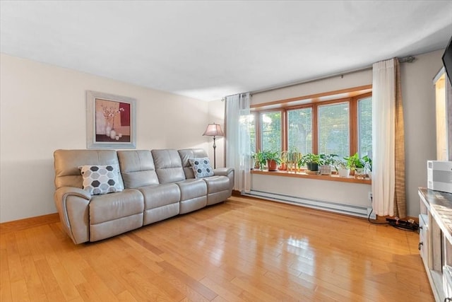 living area with a baseboard radiator, baseboards, and light wood-style flooring