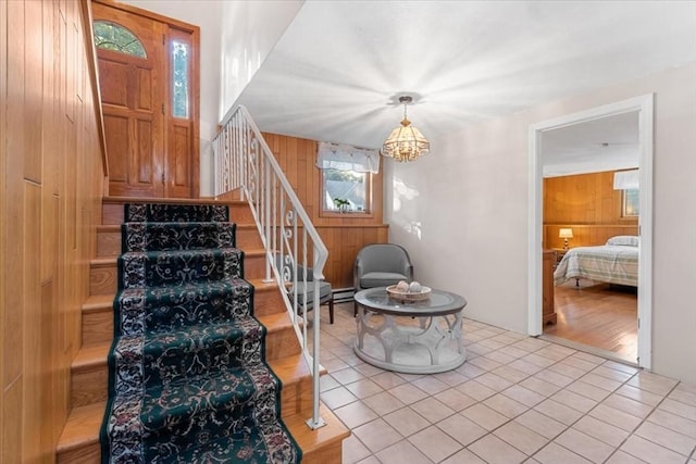 foyer with a notable chandelier, wood walls, and stairs