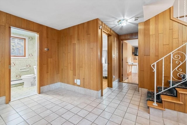 foyer entrance with wood walls, stairway, a baseboard heating unit, and light tile patterned flooring