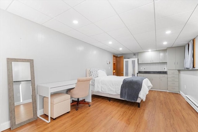 bedroom featuring a drop ceiling, recessed lighting, baseboards, baseboard heating, and light wood-type flooring