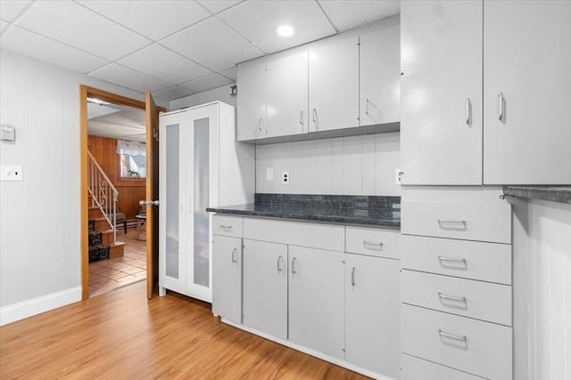 kitchen with a paneled ceiling, light wood-style flooring, and white cabinets