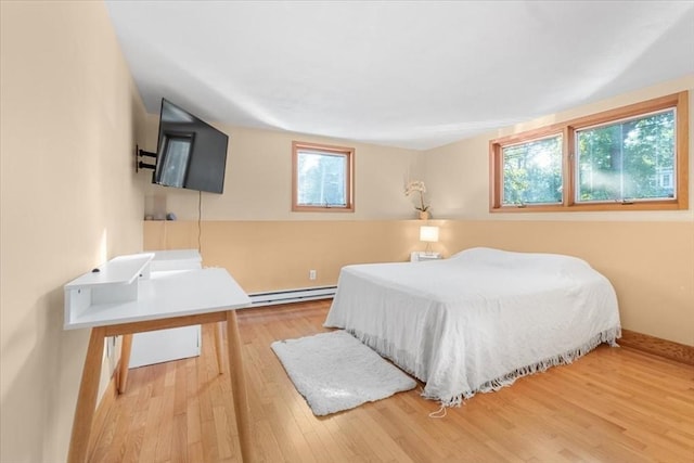 bedroom featuring a baseboard heating unit and wood finished floors