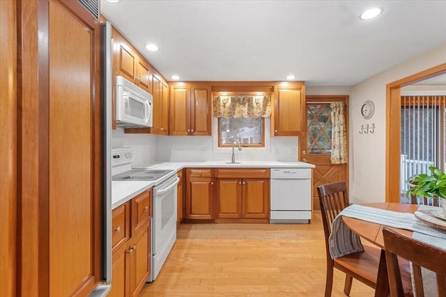 kitchen with recessed lighting, white appliances, a sink, light wood-style floors, and light countertops