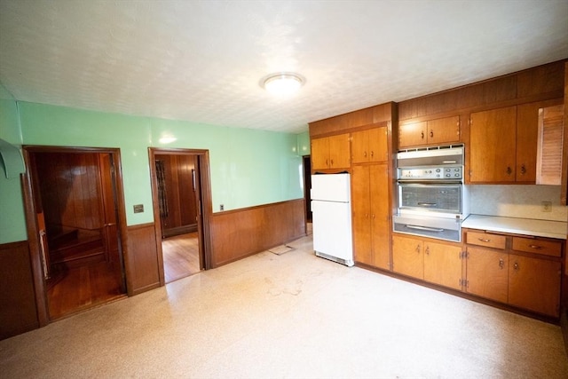 102 Margin St, Salem, MA 01970 - kitchen featuring freestanding refrigerator, wall oven, wainscoting, brown cabinetry, and a warming drawer