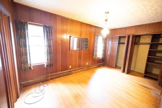102 Margin St, Salem, MA 01970 - unfurnished bedroom featuring wood finished floors, two closets, wooden walls, multiple windows, and baseboards