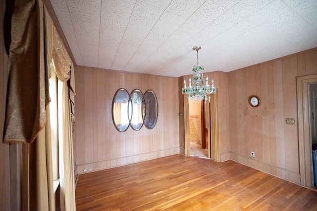 102 Margin St, Salem, MA 01970 - empty room with a chandelier, wood-type flooring, wooden walls, and baseboards