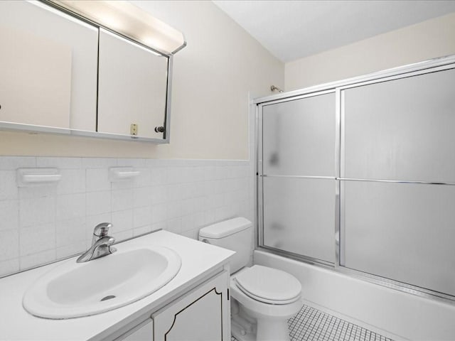 full bathroom with toilet, vanity, tile walls, combined bath / shower with glass door, and tile patterned floors