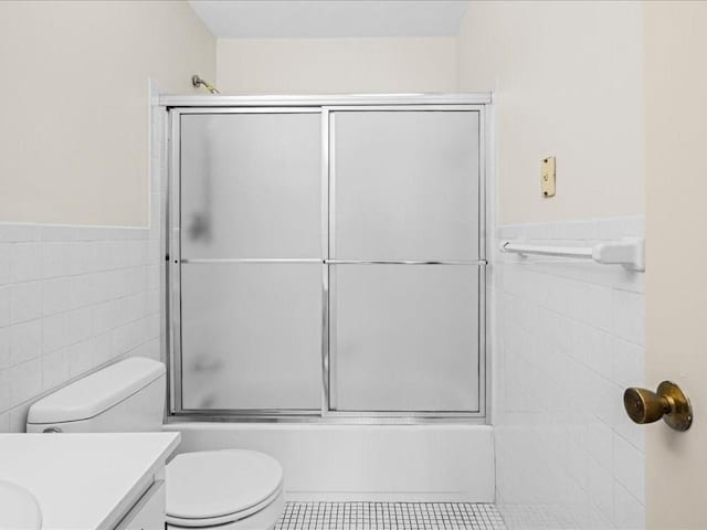 bathroom featuring a wainscoted wall, tile walls, toilet, vanity, and tile patterned flooring