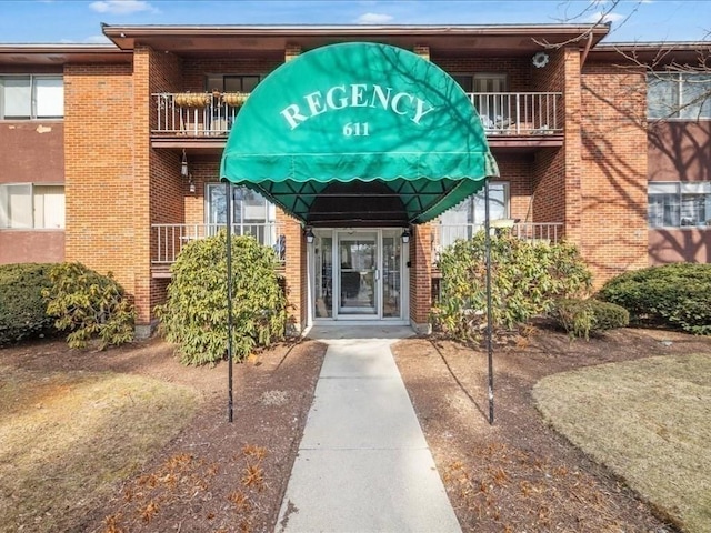 property entrance with a balcony and brick siding