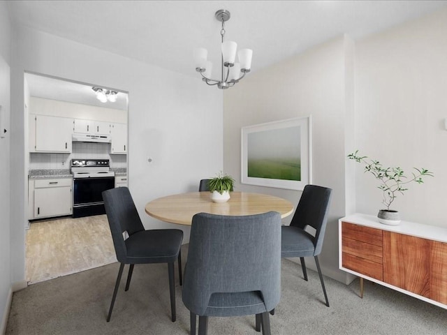 dining area with light wood-style floors, a chandelier, and light colored carpet