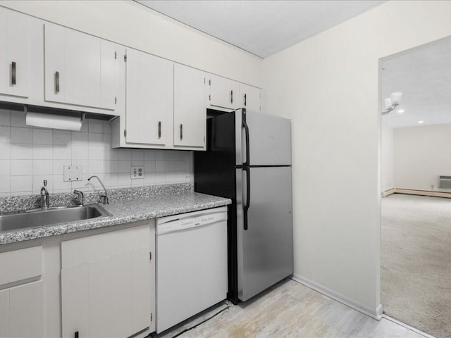 kitchen featuring freestanding refrigerator, a sink, white dishwasher, white cabinetry, and backsplash