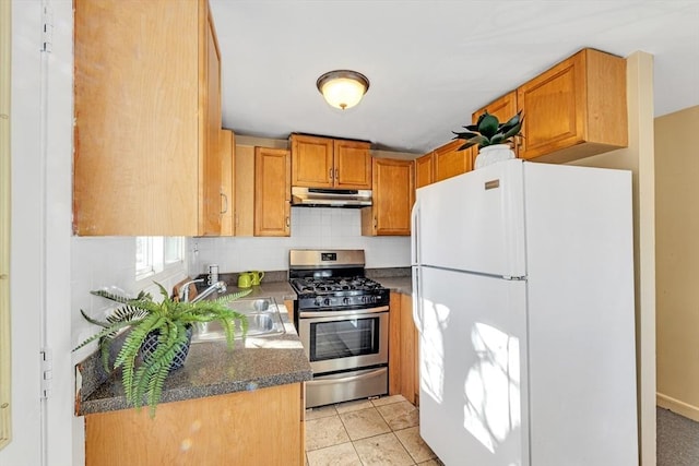 kitchen featuring light tile patterned floors, freestanding refrigerator, a sink, gas range, and under cabinet range hood