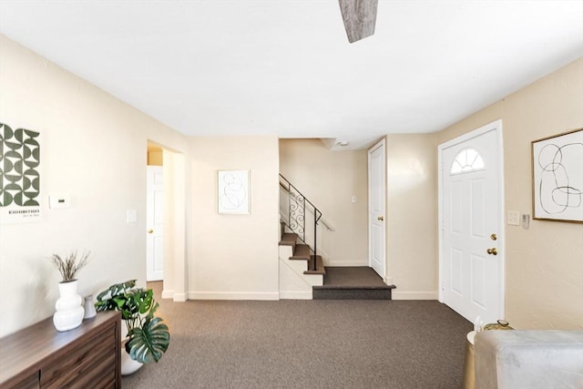 carpeted foyer with stairway and baseboards