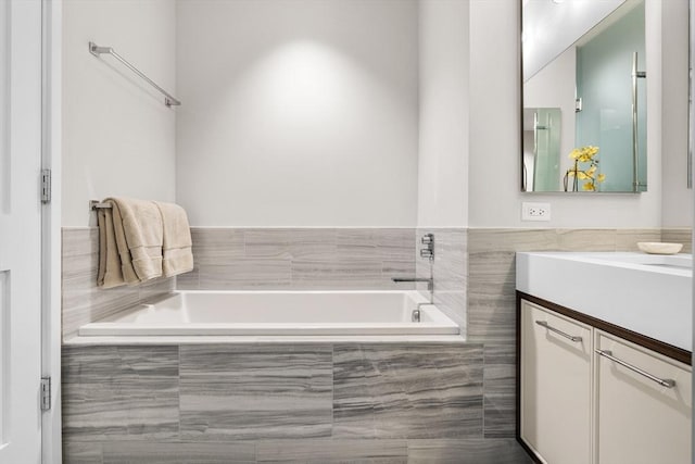 bathroom with tiled tub and vanity