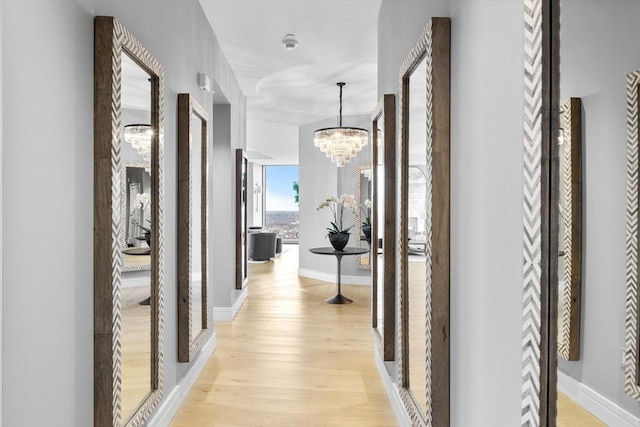 hallway with light hardwood / wood-style floors and an inviting chandelier