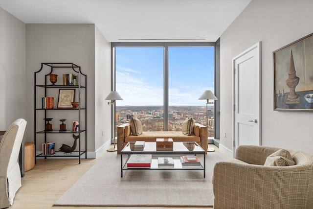 living area featuring plenty of natural light, a wall of windows, and light hardwood / wood-style flooring