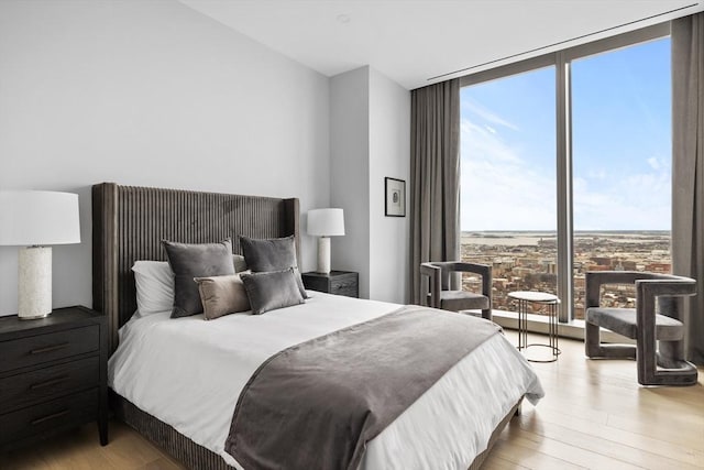 bedroom with expansive windows and light hardwood / wood-style floors