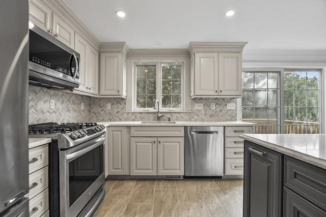 kitchen with cream cabinetry, appliances with stainless steel finishes, ornamental molding, and sink