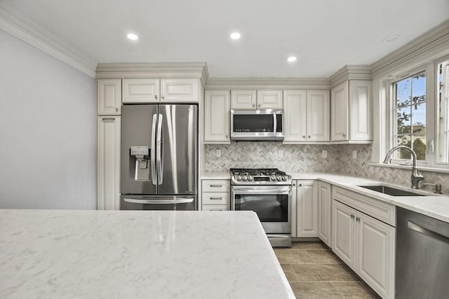 kitchen with light stone countertops, appliances with stainless steel finishes, tasteful backsplash, ornamental molding, and sink