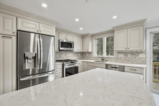 kitchen with stainless steel appliances, light stone counters, tasteful backsplash, and sink