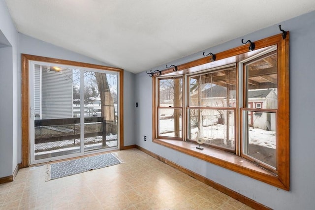 doorway with lofted ceiling, light floors, and baseboards