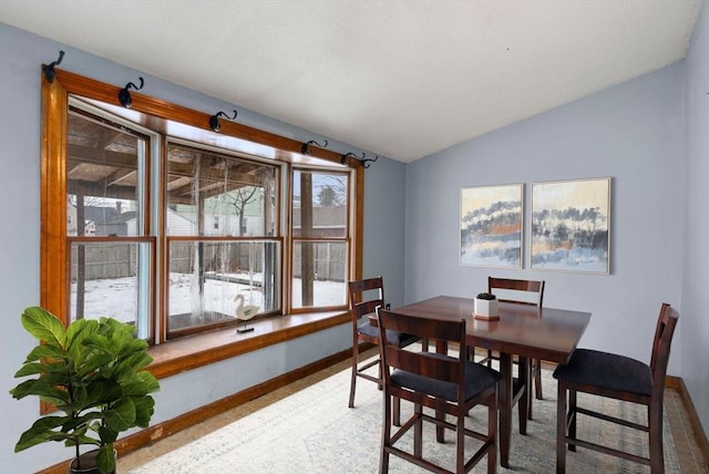 dining space with lofted ceiling and baseboards