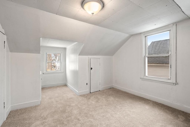 bonus room with lofted ceiling, light colored carpet, and baseboards